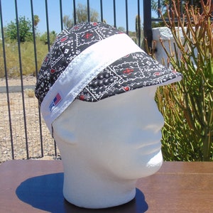 May include: Black and white bandana-style welding cap with a white band and a small American flag patch. The cap is on a white mannequin head.