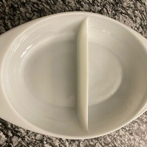 May include: White oval ceramic baking dish with a divider down the middle. The dish is empty.