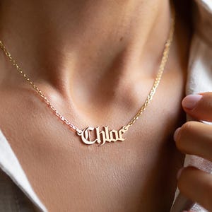 May include: A gold necklace with the name "Chloe" spelled out in a gothic font.