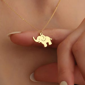K&ouml;nnte beinhalten: Eine goldene Kettenkette mit einem kleinen Elefantenanh&auml;nger. Der Elefant ist nach rechts gerichtet und hat seinen R&uuml;ssel erhoben.