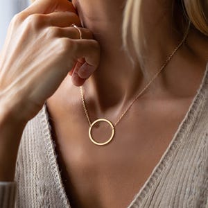 May include: A gold circle pendant necklace with a delicate chain.