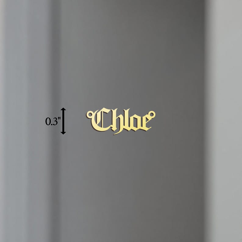 May include: Gold-colored metal charm with the name "Chloe" in a gothic font. The charm is 0.3 inches tall.