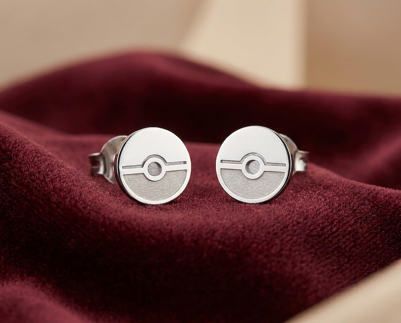 Peut inclure: Une paire de boucles d'oreilles &agrave; clous circulaires en argent pr&eacute;sentant un design divis&eacute; avec une moiti&eacute; sup&eacute;rieure polie lisse et une moiti&eacute; inf&eacute;rieure mate textur&eacute;e, s&eacute;par&eacute;es par une ligne horizontale et un cercle central.