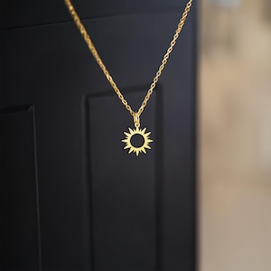 以下が含まれることがあります： 太陽のペンダントが付いたゴールドチェーンネックレス。太陽のペンダントは、縁から伸びる光線を持つシンプルなオープンサークルです。