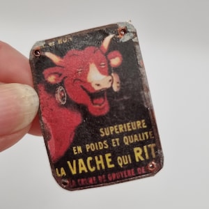 Cartel publicitario del queso La vache qui rit en estado desgastado