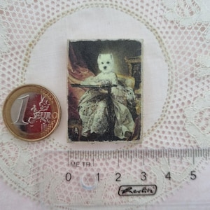 May include: A small rectangular image featuring a dog dressed in period clothing, reminiscent of a portrait. A Euro coin and a clear ruler with metric measurements are next to the image. The image is on a white lace doily.