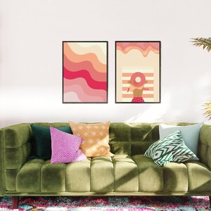 Pink preppy poster set with illustrations hangs on the wall in a living room above the green sofa
