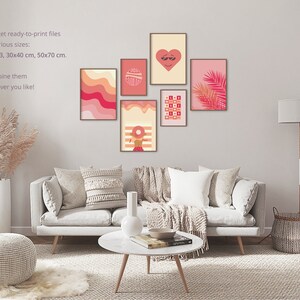 Pink preppy wall art of posters with orange pink illustrations hangs on the wall in a living room above the beige sofa