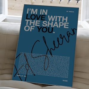 May include: A blue poster with white text that reads "I'm in love with the shape of you."  The poster also includes the artist's name, Ed Sheeran, and his signature in black. The lyrics to the song "Shape of You" are printed in white on the poster.