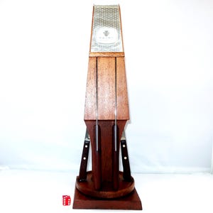 May include: A wooden knife block with a dark finish, holding several knives. The block has a tall, tapered design with a decorative top. The knives have black handles and silver blades. A red die is in the foreground.