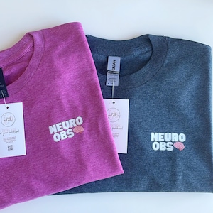 May include: Two t-shirts, one pink and one dark blue, with the text "NEURO OBS" and a small brain graphic embroidered on the front.