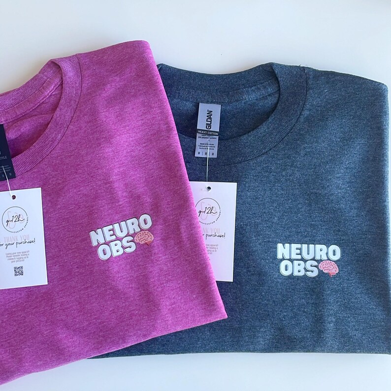 May include: Two t-shirts, one pink and one dark blue, with the text "NEURO OBS" and a small brain graphic embroidered on the front.