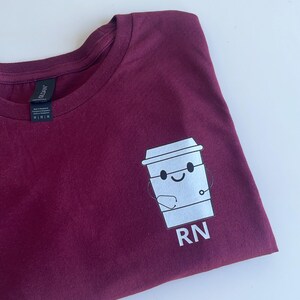 May include: A maroon t-shirt with a white graphic of a coffee cup with a stethoscope and the text "RN".