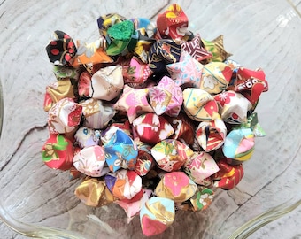 May include: A bowl filled with colorful origami lucky stars. The stars are made of patterned paper and have a variety of designs, including floral, geometric, and abstract patterns.