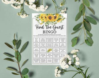 May include: A white bingo game card with the text "Find the Guest Bingo" and sunflower graphics. The card includes various prompts for guests to mingle and find matches. The card is surrounded by white flowers and green foliage.