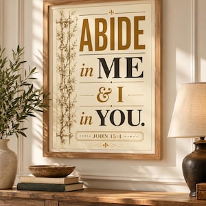 May include: A rectangular framed wall art piece featuring a cream-colored background with the text ABIDE in ME & I in YOU. JOHN 15:4 printed in dark brown and gold. A vertical illustration of a flowering vine on a trellis is on the left side.