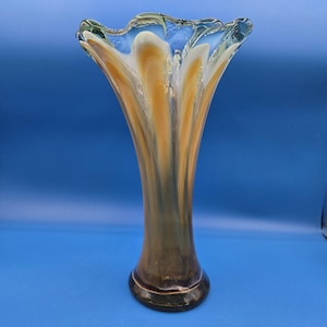 May include: A tall, flared glass vase with a ruffled rim. The vase features a blend of colors, including amber, white, and brown, with a dark base. The vase is approximately 12 inches tall, suitable for displaying flowers or as a decorative piece.