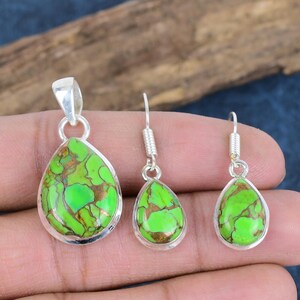 May include: A set of green turquoise gemstone jewellery with silver settings. The set includes a pendant and a pair of earrings. The pendant and earrings are all teardrop shaped.