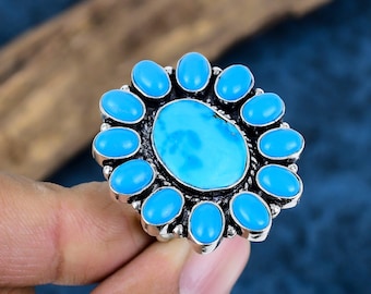 Puede incluir: Un anillo de plata con una piedra turquesa grande rodeada de piedras turquesa más pequeñas.