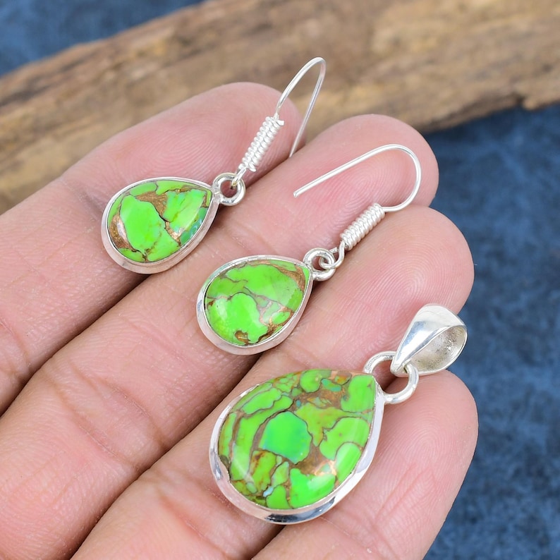 May include: A set of silver earrings and a pendant featuring green turquoise stones with copper accents. The stones are teardrop shaped and set in silver.