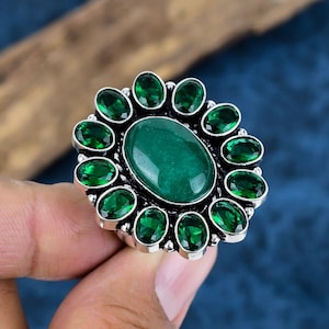 May include: A silver ring with a large oval green stone surrounded by smaller green stones.