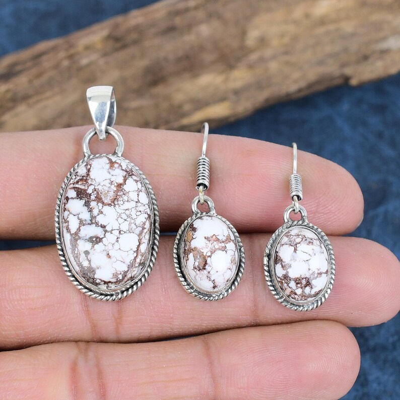 May include: A set of silver earrings and a pendant featuring white and brown oval-shaped stones with a marbled pattern.