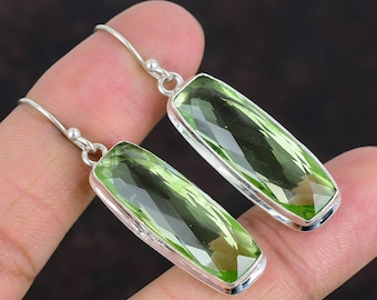 May include: A pair of silver dangle earrings with rectangular green gemstones. The earrings have a simple design and are perfect for everyday wear.