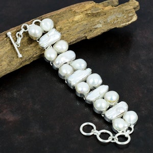 May include: A white freshwater pearl bracelet with a silver toggle clasp. The pearls are irregular in shape and size, and are set in silver.