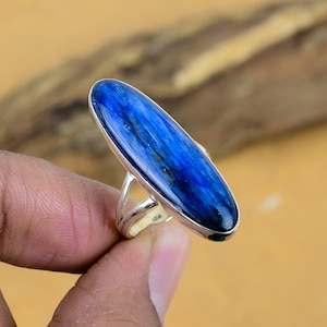 May include: A silver ring featuring a blue oval-shaped gemstone. The gemstone has a striated pattern.