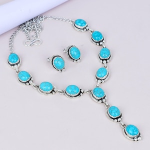 以下が含まれることがあります： シルバーカラーのジュエリーセット。ネックレスとイヤリングのセットで、ネックレスは楕円形のターコイズ色の石が装飾的なシルバーのセッティングにセットされています。イヤリングも同様のデザインで、ターコイズ色の石が使われています。