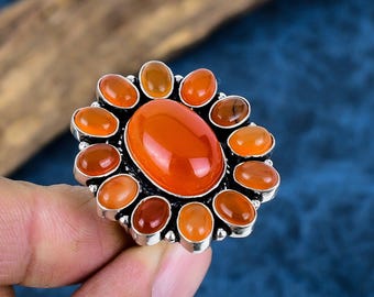 Könnte beinhalten: Ein silberner Ring mit einem großen ovalen orangefarbenen Edelstein, umgeben von kleineren orangefarbenen Edelsteinen.