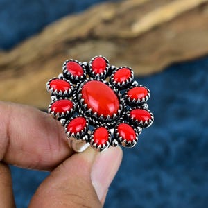 May include: A silver ring featuring a cluster of red coral stones set in a floral design.