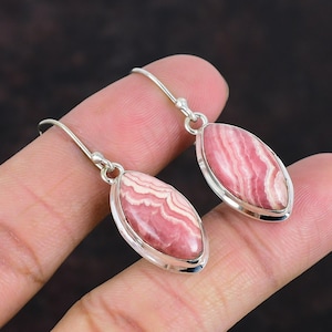 May include: A pair of silver dangle earrings with pink and white striped oval-shaped gemstones.
