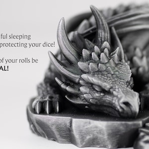 An extreme close-up of the sleeping dragon's head, highlighting the fine 3D-printed textures of its scales and horns in a metallic finish. To the left, stylized text reads: "A beautiful sleeping dragon, protecting your dice! May all of your rolls be CRITICAL!" The focus is tight on the dragon's peaceful face, conveying a sense of quality and craftsmanship.