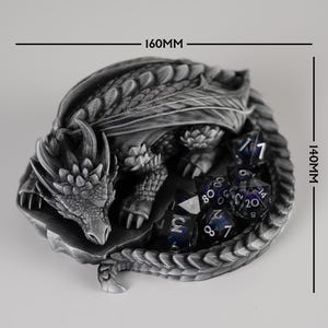 A top-down product size guide for the Nap Twenty dragon dice holder. The 3D-printed silver dragon is shown coiled around a set of purple dice, with black dimension lines indicating a width of 160mm and a depth of 140mm. The image clearly illustrates the footprint of the dice tray for tabletop gaming space planning.
