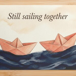 May include: Watercolor illustration of two paper boats sailing on dark blue waves under a light brown sky. The text "Still sailing together" is written above the boats.
