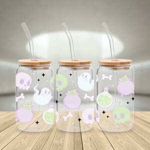 May include: Three clear glass jars with bamboo lids and matching straws. Each jar has a Halloween-themed design with ghosts, skulls, cauldrons, bones, and potion bottles in shades of green, purple, and white.