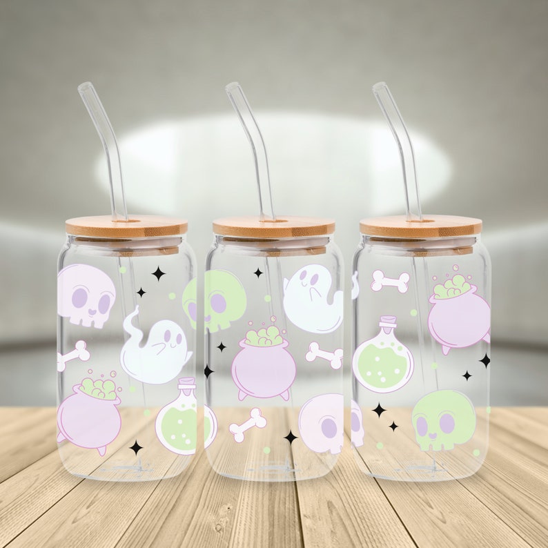 May include: Three clear glass jars with bamboo lids and matching straws. Each jar has a Halloween-themed design with ghosts, skulls, cauldrons, bones, and potion bottles in shades of green, purple, and white.