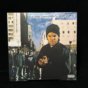 May include: Album cover for Ice Cube's "AmeriKKKa's Most Wanted." The image features Ice Cube in a black beanie and jacket, set against a city backdrop. The album title and parental advisory warning are visible.