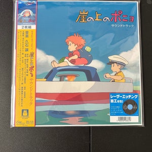 May include: A blue and white vinyl record cover featuring a picture of a girl and a boy on a boat. The title of the record is "崖の上のポニョ" (Gake no Ue no Ponyo) and the text "サウンドトラック" (Sound Track) is below the title. The record is a 2-disc set and features music by Joe Hisaishi.
