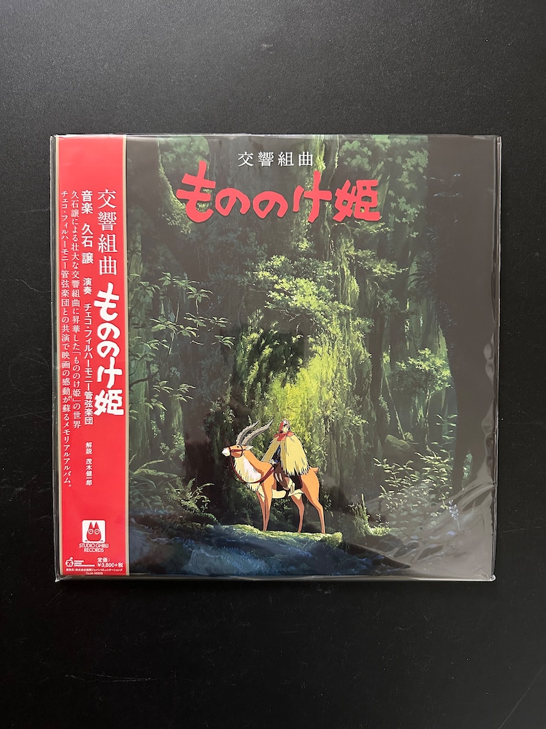 May include: A vinyl record album cover featuring a green and brown forest scene with a person riding a deer-like creature. The album title is "もののけ姫" (Mononoke Hime) in Japanese characters. The album is a soundtrack for the film "Princess Mononoke".