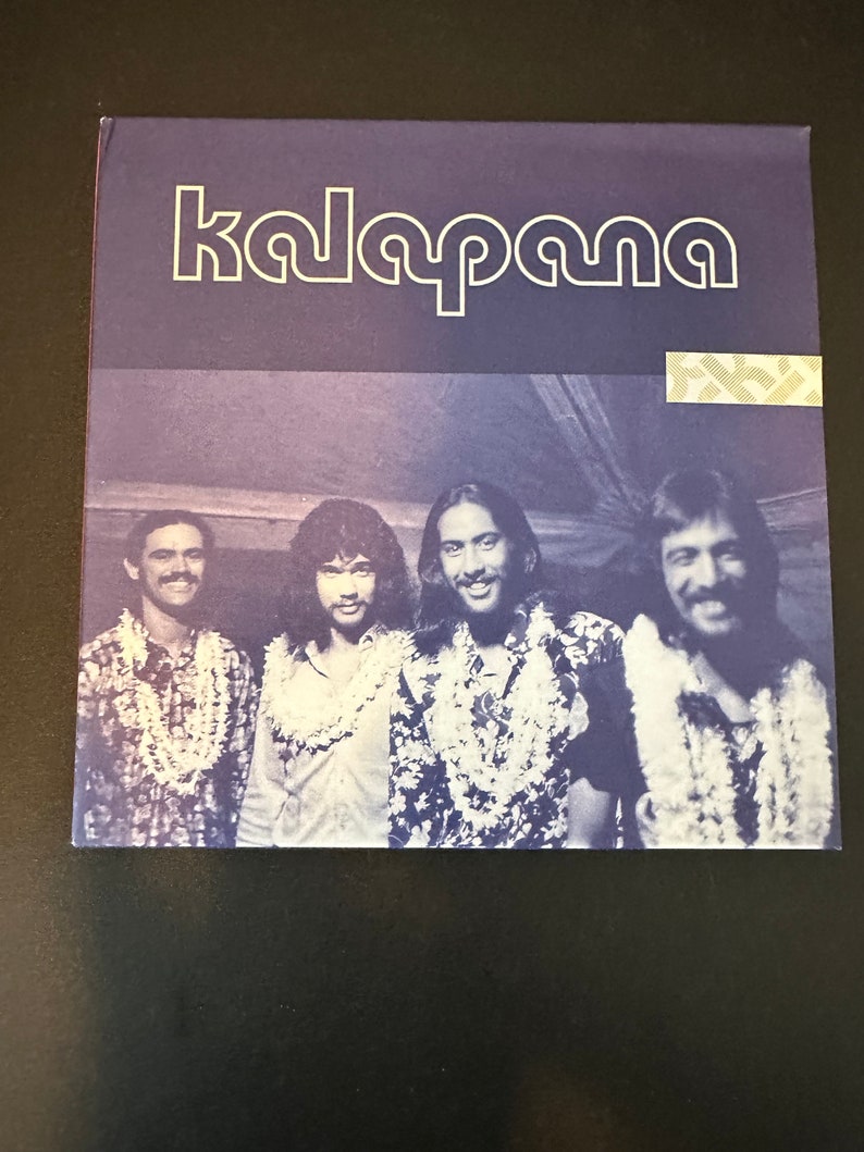 May include: A vintage record album cover featuring a band called "kalapana". The cover features a photo of four men wearing floral leis and smiling at the camera.