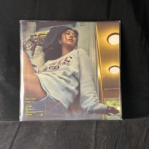 May include: A vinyl record album featuring a woman wearing a gray sweatshirt with the text "UNITY" and the number "69" printed on it. The album cover has text in Japanese and English, with the title "Mine or Yours". The album is sealed in plastic.