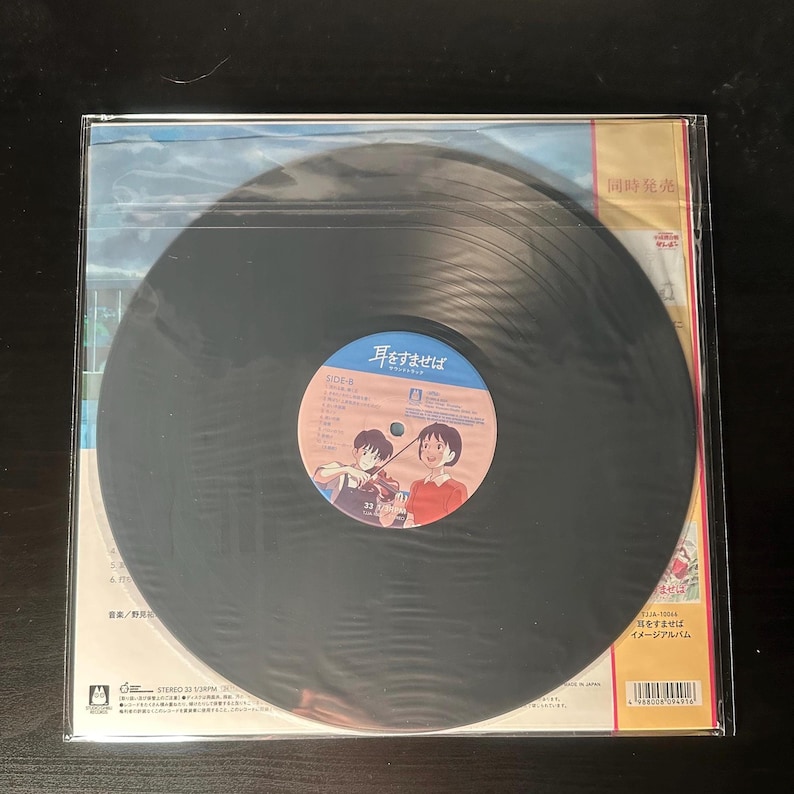 K&ouml;nnte beinhalten: Schwarze Vinyl-Schallplatte in einer transparenten Plastikh&uuml;lle. Das Album hat ein blau-wei&szlig;es Etikett mit japanischem Text und Cartoon-Illustrationen. Das Albumcover enth&auml;lt ebenfalls japanischen Text.