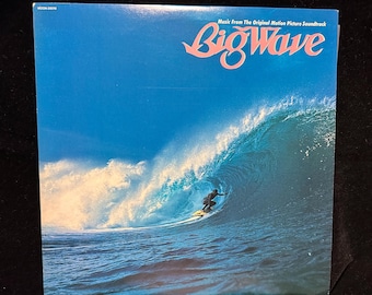 May include: Album cover for "Big Wave" soundtrack. The image features a surfer riding a large wave, with the wave's curl creating a tunnel. The album title is in a stylized, pink script. The background is a gradient of blue.