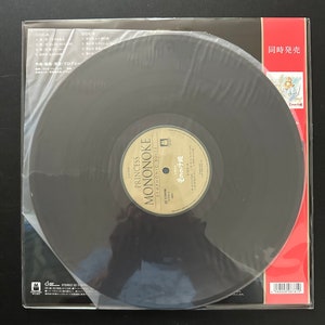 May include: A black vinyl record with a white label that says "Princess Mononoke Symphonic Suite" and "もののけ姫". The record is in a clear plastic sleeve with a red and white label that says "Simultaneous Release".