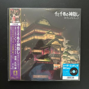 May include: Sealed vinyl record of the "Spirited Away" soundtrack. The album cover features a detailed illustration of a traditional Japanese building at night. Japanese text is visible on the cover, along with a sticker indicating laser etching.