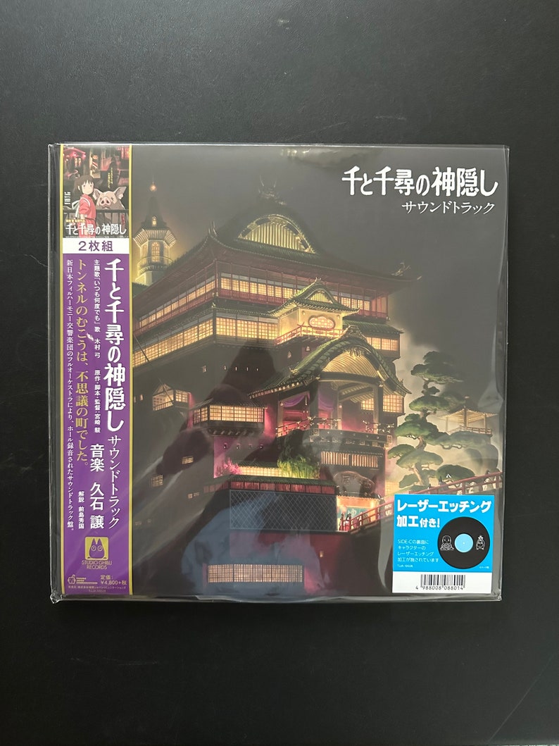 May include: Sealed vinyl record of the "Spirited Away" soundtrack. The album cover features a detailed illustration of a traditional Japanese building at night. Japanese text is visible on the cover, along with a sticker indicating laser etching.