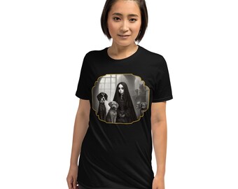 May include: Black t-shirt with a gothic illustration. The design shows a woman in a dark dress with dogs, framed within a decorative border. The t-shirt is made of a soft material.