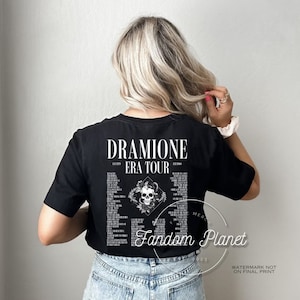 May include: Black t-shirt with a white graphic of a skull with snakes and the text "Dramione Era Tour" and "Fandom Planet".